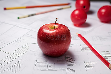 坐在铅笔上背景图片_一个红苹果坐在一些纸和红铅笔上