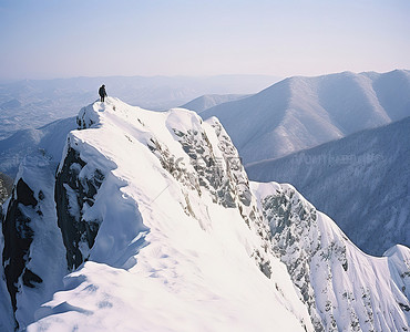 一个男人站在白雪覆盖的悬崖边山旁