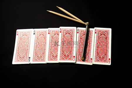 扑克牌桌子背景图片_桌子上铺着六张扑克牌，旁边是一根棍子，另一根在前面