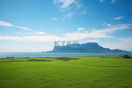 海水边背景图片_水边绿色田野和地平线上一座山的俯视图