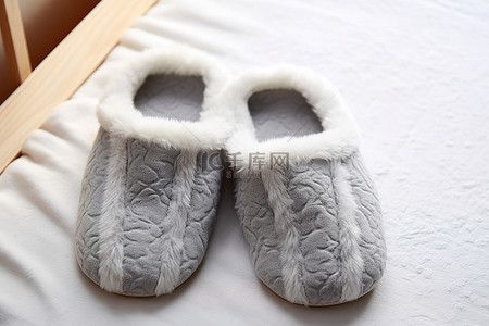 白色拖鞋垫上放着两只带有舒适毛皮的灰色拖鞋