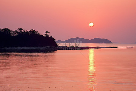 背景海背景图片_粉红色的太阳照耀着岛屿附近的浅海