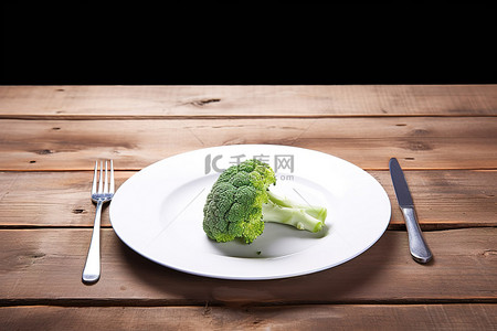 木凳上放着一个空盘子，上面有生菜和西兰花