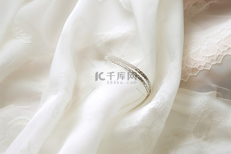 银色结婚戒指位于白色蕾丝礼服之上
