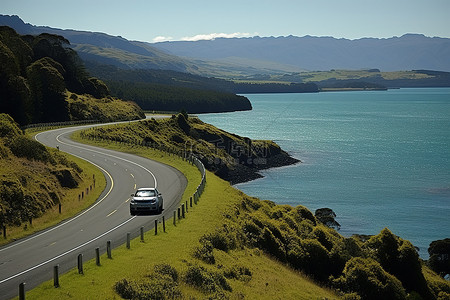 汽车旅游背景图片_汽车行驶在新西兰怀马特群岛湾旁边的一条长路上