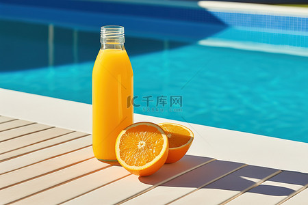 池边桌子上放着一瓶橙汁和橙子