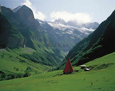 欧洲的。红色的背景图片_绿色的山坡，有圆锥形帐篷和周围的红色山脉