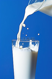 牛奶被倒入蓝色背景的玻璃杯中