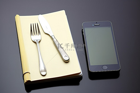 笔记本和叉子旁边的手机