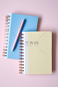 两个笔记本，里面有粉色和蓝色的笔