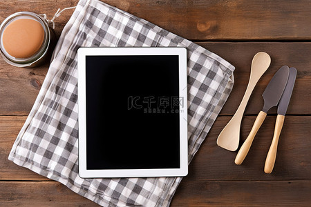 炊具刀抹布抹布和木桌上的黑色 ipad 平板电脑屏幕