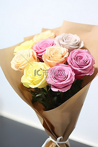 彩色玫瑰背景图片_棕色保鲜膜中的彩色玫瑰花束