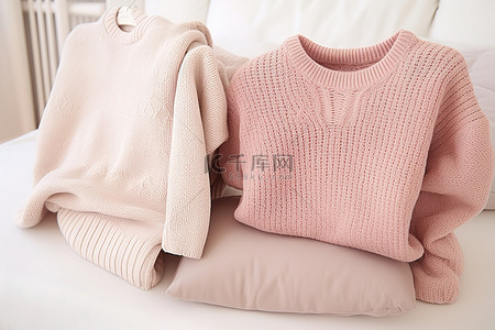 三件毛衣放在白色床上，营造出舒适的冬季外观