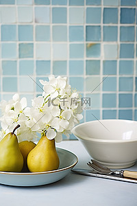 蓝白瓷砖墙上放着一个白盘和一碗梨，上面有花