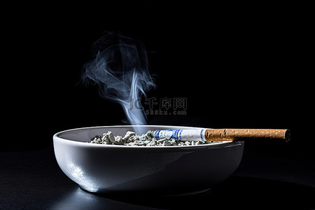 黑色背景下的白色碗里放着一支香烟
