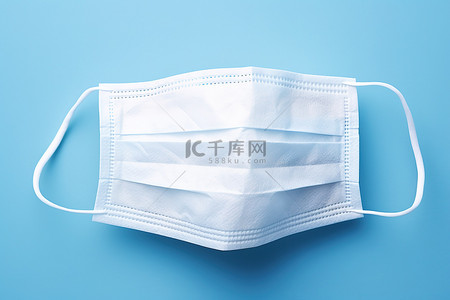 肺炎背景图片_蓝色表面上的白色一次性手术口罩