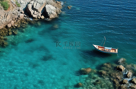 海中岩石背景图片_蓝色海洋中的一艘船和岩石