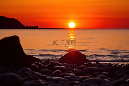 落背景图片_太阳落在一片水体上，背景是岩石