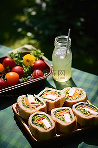 三明治坐在绿色的桌子上，上面有水果和饮料