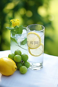 一杯果汁和水，旁边有一块柠檬角，靠近五颜六色的水果