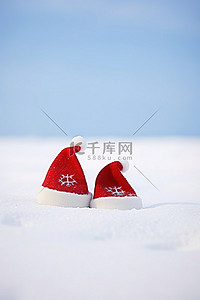 防寒帽子背景图片_雪地里的一对圣诞老人帽子
