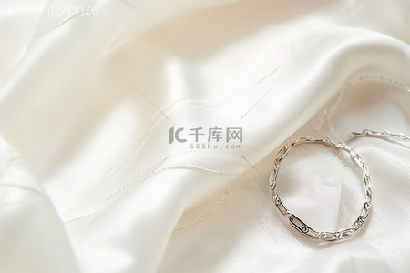 礼服文案背景图片_银色结婚戒指位于白色蕾丝礼服之上