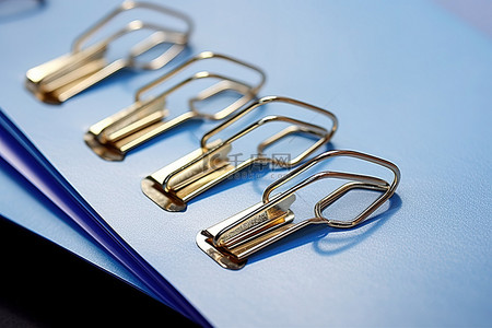 银色文件夹子背景图片_蓝色文件夹顶部有五个银色金属夹