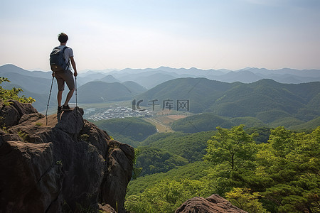 一个带着攀爬架的年轻人站在岩石顶上，周围的景色很美