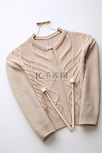 温暖毛衣背景图片_一件毛衣和织针放在白色表面上