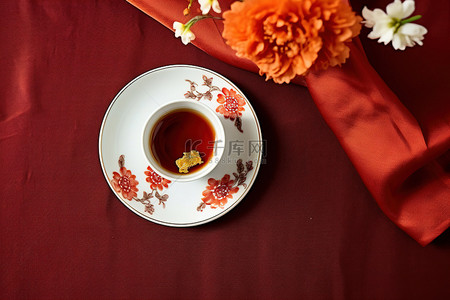 红布上放着中国茶杯和鲜花的盘子