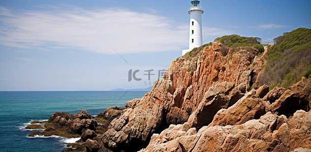 悬崖上的人背景图片_一座白色灯塔坐落在岩石悬崖上