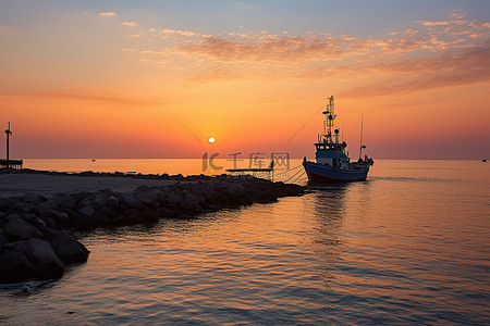 海岸防波堤背景图片_太阳从海岸的一艘渔船上升起