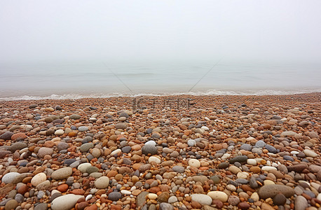 复活岛石像背景图片_威斯敏斯特剑桥郡汉普斯特德海滩岸边雾中的圆石滩
