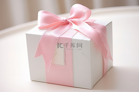 一个白色盒子，上面有一条粉红色丝带和一个标签