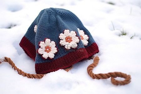 一顶蓝色无檐小便帽躺在雪地上，开着白花
