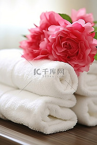 一叠白色毛巾与粉红色花束一起排列
