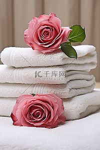 一叠毛巾，上面并排放着红玫瑰