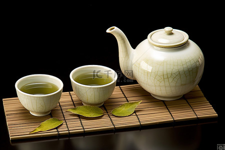 一个绿茶壶两个杯子和一些叶子