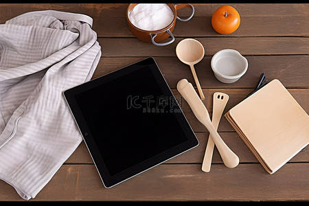 ipad皮夹背景图片_炊具刀抹布抹布和木桌上的黑色 ipad 平板电脑屏幕