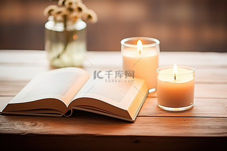 木桌上一本打开的书旁边坐着两根蜡烛