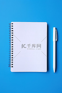 圆珠笔蓝色背景图片_蓝色背景上白色笔旁边的白色记事本