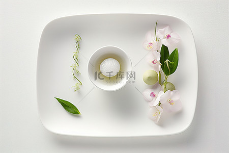 浴背景图片_一个白色的小盘子，上面放着一杯茶和鲜花