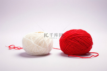白色的球背景图片_一个红色的毛线球坐在一个白色的毛线球旁边