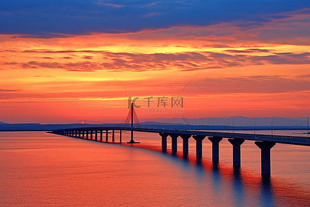 夕阳落下背景图片_夕阳下的一座桥在水面上落下