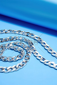 异域风珠链背景图片_蓝色桌子上的两个银色链节