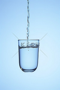 蓝色背景水背景图片_装满水的水杯落到蓝色背景上