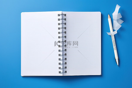 圆珠笔蓝色背景图片_蓝色背景上的空笔记本打开铅笔和卷笔刀