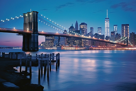 美国泰克背景图片_当布鲁克林大桥在黄昏时分被点亮时，蓝色的灯光出现在水面上