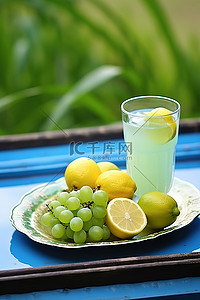 零食干果盘背景图片_蓝盘上的柠檬饮料和葡萄