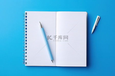 圆珠笔蓝色背景图片_亮蓝色背景上的空白笔记本和铅笔